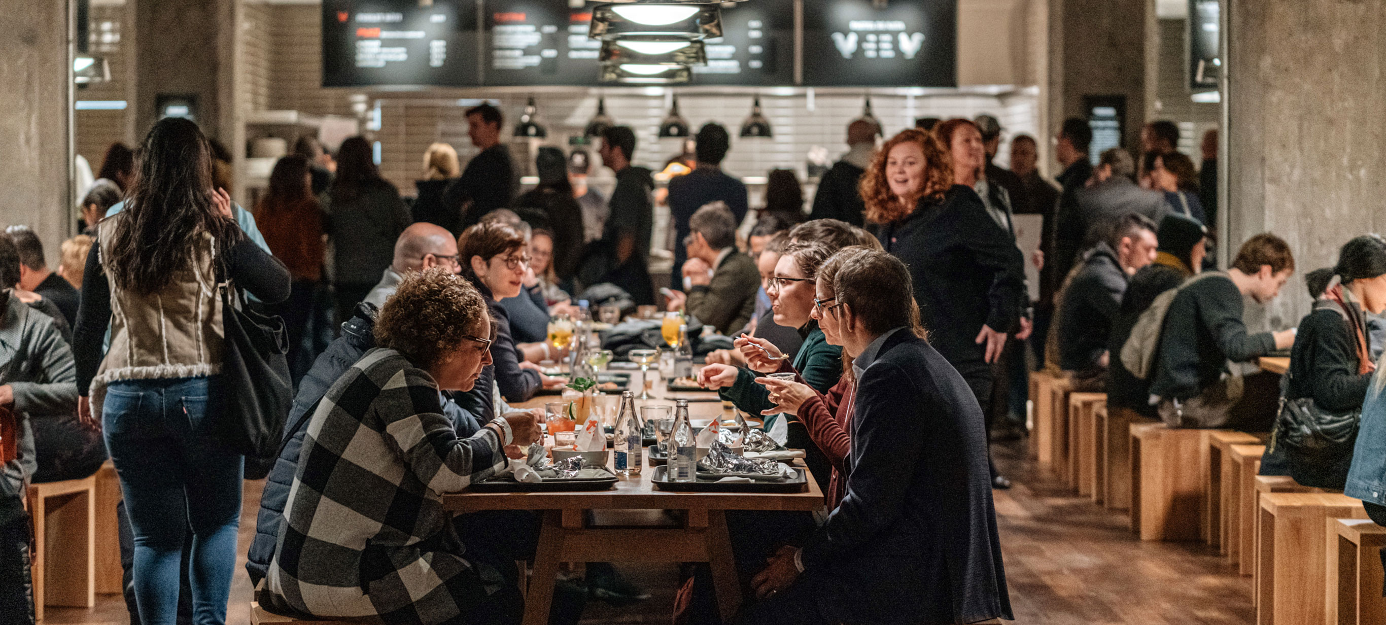 Personnes mangeant à une table commune au Time Out Market Montréal